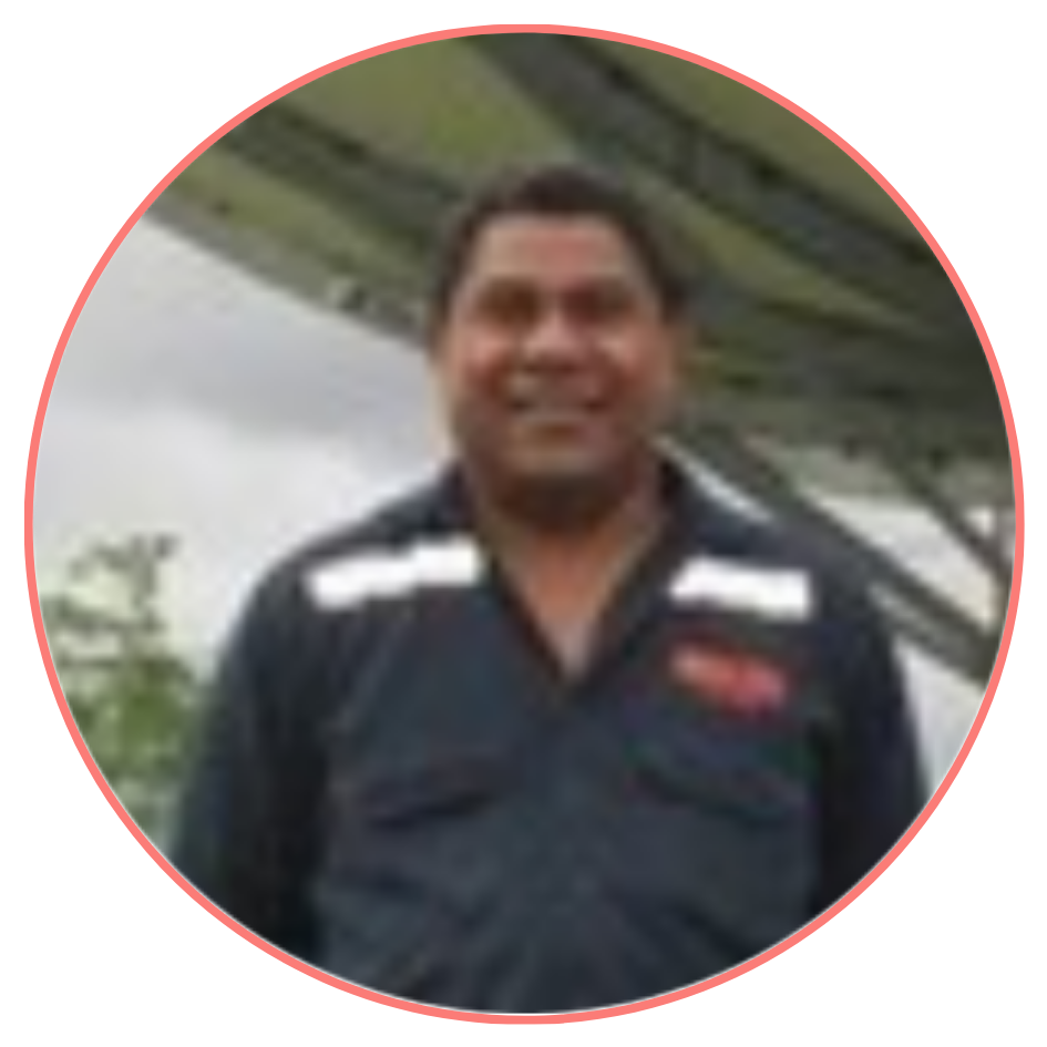 A smiling man in a dark uniform, standing outdoors with blurred greenery in the background, framed within a circular border.