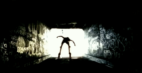 A person breakdancing in a graffiti-covered tunnel, silhouetted against the brightly lit background of an IT service desk.