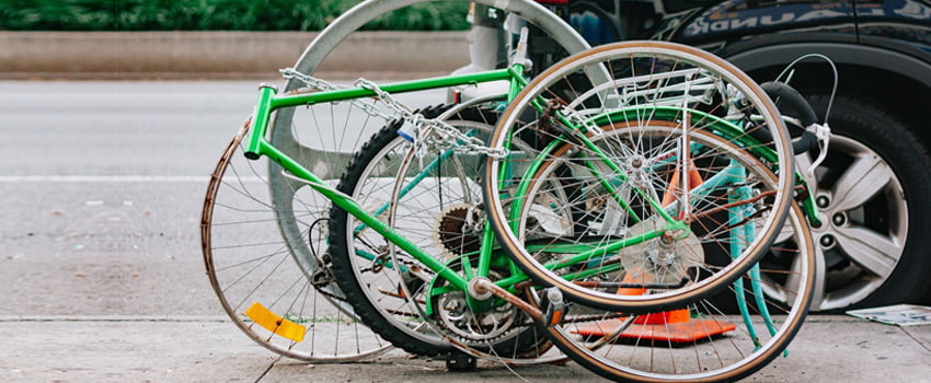 Two green bicycles with missing parts locked to a pole, highlighting the need for IT Asset Management (ITAM) efficiency. - SysAid