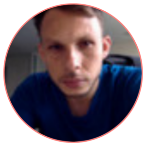 A man with short hair and in a blue shirt, looking directly at the camera, enclosed within a red circular border.