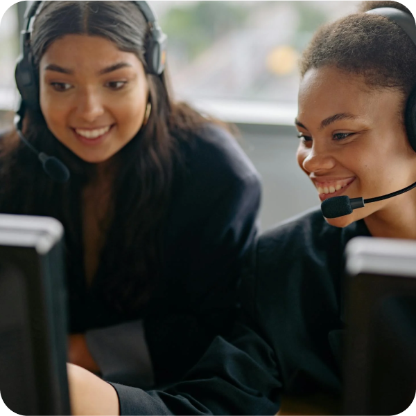 Two women collaborate at computers, delivering excellent Service Desk support with SysAid’s ITSM solutions. - SysAid