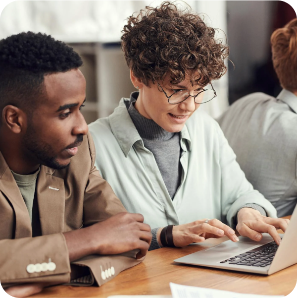 Three colleagues collaborate at a table with a laptop, streamlining ITSM tasks using SysAid Service Desk solutions. - SysAid