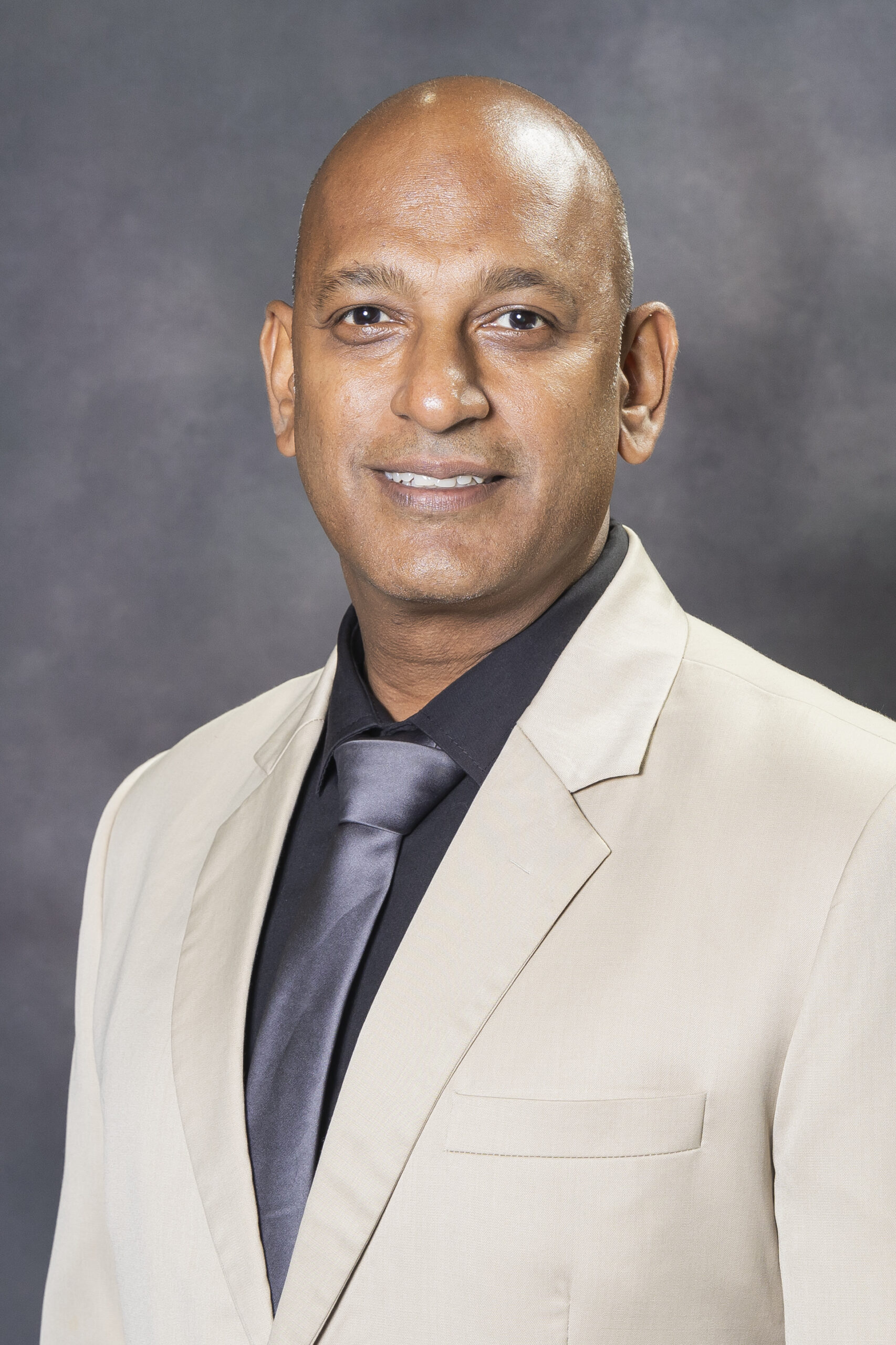 Professional man in suit and tie, reflecting SysAid’s ITSM expertise, posed for a portrait against a dark background. - SysAid