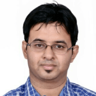 Portrait of a man with glasses, wearing a blue checkered shirt, against a white background.