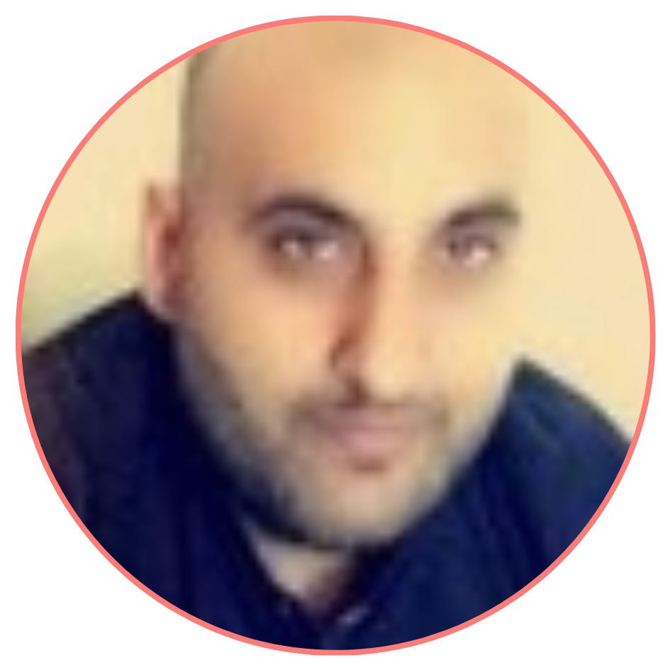 A man with a shaved head and a beard, wearing a dark shirt, in a circular frame, slightly blurred, looking at the camera.